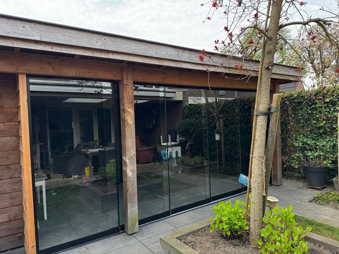 Houten overkapping met glaswanden in de tuin