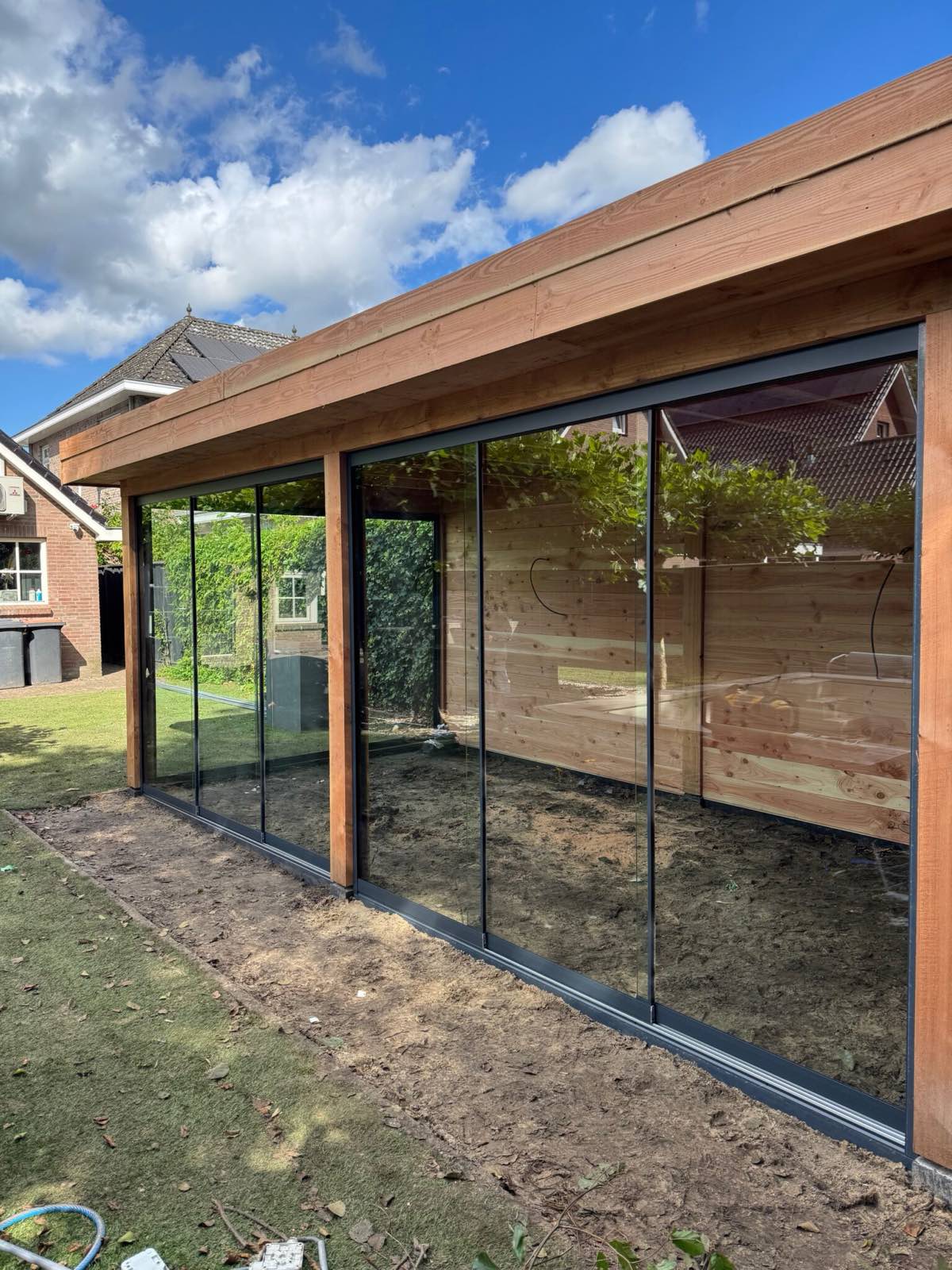 Houten veranda met glazen wanden in een Twentse achtertuin