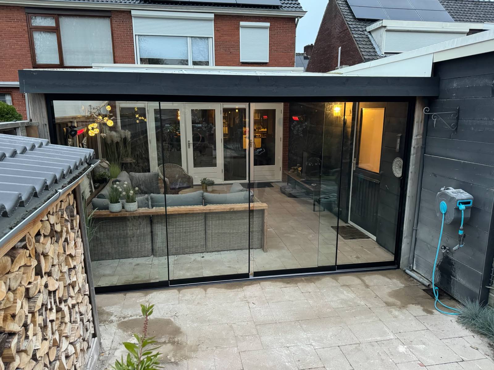 Op maat gemaakte houten overkapping met glazen schuifwanden in een Twentse tuin