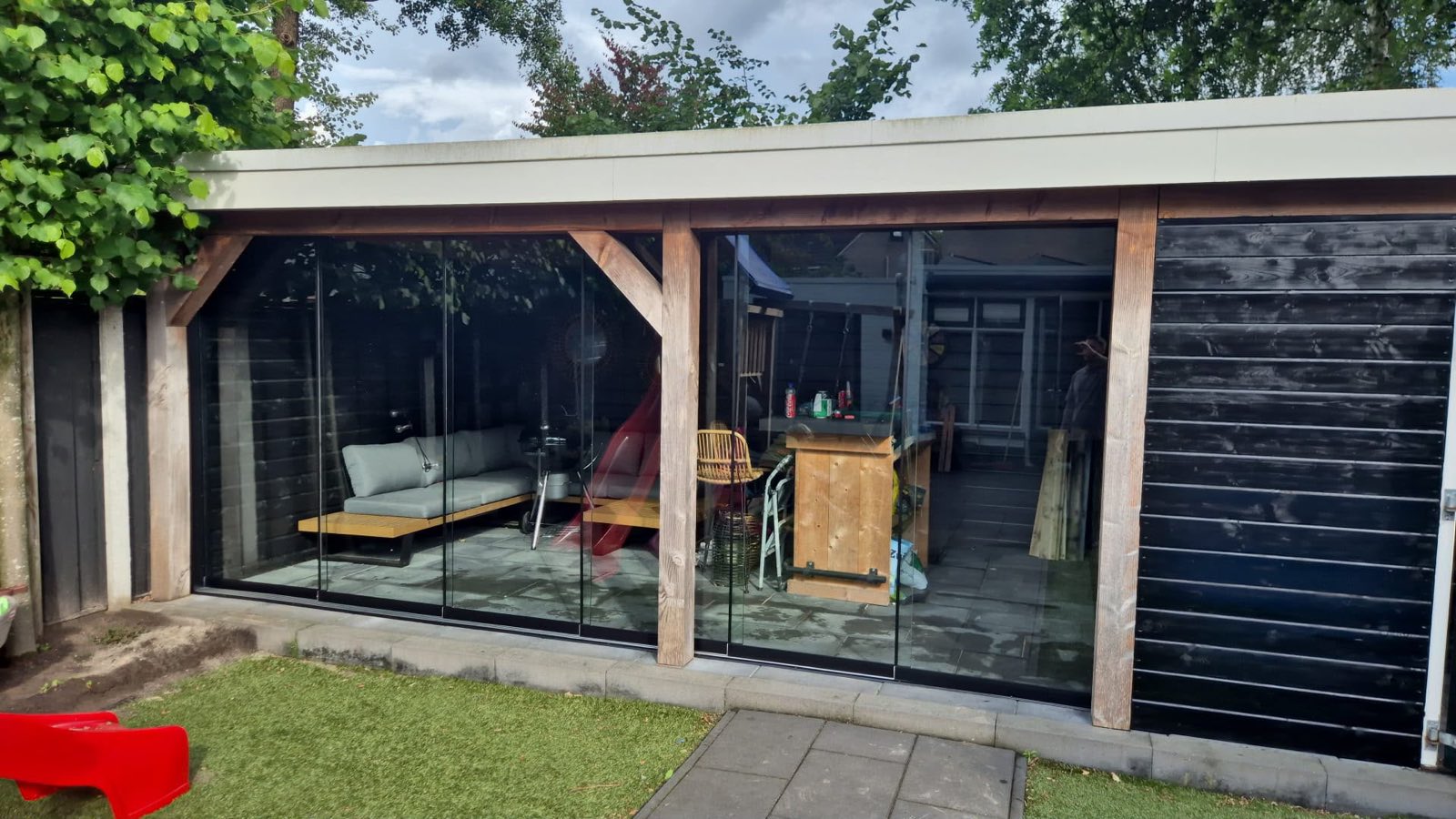 Zwarte houten overkapping met glaswanden en loungebar